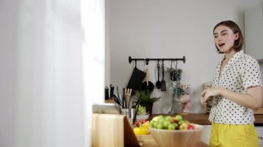 Mutlu genç anne mutfakta dururken salata kasesine sebze koydu. Çekici beyaz bir kadın yemek pişirmekten ve sabah taze organik yemek yapmaktan ya da ev yemeği yapmaktan zevk alır. Pedagoji.