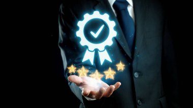 Bir işadamı, profesyonel bir ortamda başarı ve mükemmelliğin vurgulandığı bir ödül sembolü ve işaretli bir işaret sunar. Koyu arkaplan görüntü etkisini arttırır. Dörtgen