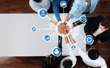 Masa etrafında işbirliği yapan, dijital simgelerle bağlantılı elleri gösteren, yenilik, teknoloji ve iş verimliliğini temsil eden farklı bir ekibin üst görüşü. Dostluk