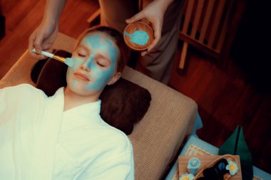 Kaplıca salonunun sakin atmosferi, kadın müşteri sıcak mum ve lüks yüz kremi masajıyla kendini yenileme zevkine kapılıyor. Yüz bakımı ve güzellik konsepti. Sessiz.