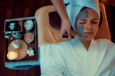 Kaplıca salonunun sakin atmosferi, üst düzey kadın müşteri sıcak mum ışığında kömür kömürü yüz kremi masajıyla kendini yenilemeye çalışıyor. Yüz bakımı ve güzellik konsepti. Sessiz.