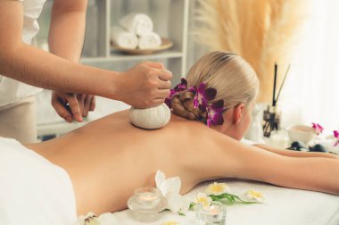 Sıcak bitkisel top spa masaj vücut tedavisi, masör kadın vücuduna nazikçe şifalı bitki torbası bastırıyor. Aromaterapi dinlenme sükuneti ve sükuneti kaplıca salonundaki atmosferi aydınlatıyor. Sessiz.