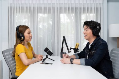 Gülümseyen radyo etkili sunucusu kulaklık takıyor kadın konuşmacı ile röportaj yapıyor sosyal medya internet sitesinden dinleyicilere bilgi paylaşıyor stüdyo kaydında sabah canlı yayın kanalı. İnfobahn.