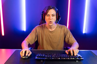 Kazanmak için çevrimiçi oyun oynayan akıllı flama makinesinin sunucu kanalı, neon ışıklı odada seçilen takım yarışması için izleyicilerle birlikte canlı yayında canlı yayında kulaklık takıyor. Bireysel.