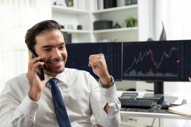 Gülümseyen tüccar işadamının yumruğunu kaldırması, borsa yatırım analizi ekranına karşı telefonla araması ve merkez ofise yüksek kârlı bir finans teknolojisi piyasası yatırması konusunda başarılı oldu. Tahmin et..