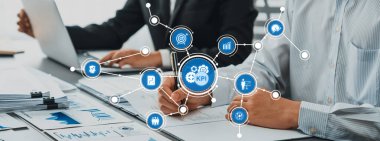 Modern ofis ortamında dijital çizelge ve grafiklerle anahtar performans göstergelerini analiz eden iş adamları, takım çalışması ve veri odaklı karar verme mekanizmasını sergiliyorlar.