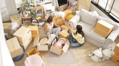 Oturma odasında karton kutuyla oturan mutlu çift kutudan mobilya topluyor. Lezbiyen aşığın yeni bir daireye ya da eve taşınırken konuştuğu en iyi manzara. Kız aşkı. Myrmidon.