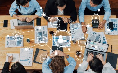 Çeşitli profesyonellerden oluşan bir grup, işbirlikçi veri analizi ve strateji geliştirme, modern bir ofis ortamında takım çalışması ve teknoloji sergiliyor. Dostluk