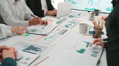 Bir grup iş adamı modern bir çalışma alanında işbirliği yaparak, finansal tablolar ve verileri analiz ederek, ekip çalışması yoluyla büyüme ve başarı için strateji oluştururlar. SACTR