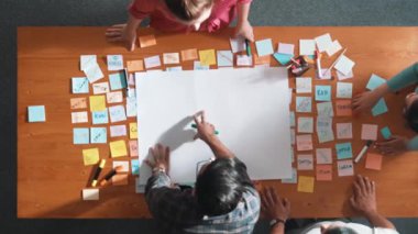 Akıllı iş adamlarının üst görüşü, proje yöneticisi toplantı masasında toplantı masasındaki pazarlama fikrini kurul odasındaki yapışkan notlar ve ekipmanlarla planlarken ve tartışırken plan hakkında konuşuyor. Sempozyum.