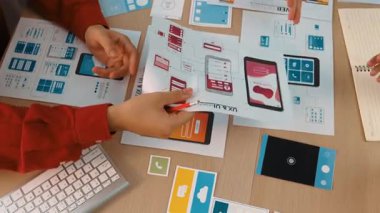 Mobil uygulama için kullanıcı arayüzü prototipini ofis çalışanlarına sunan harika bir şirket çalışanı. UX UI tasarımcısı kağıt üzerinde simge tasarımının işlevini açıklıyor. Sinerjik