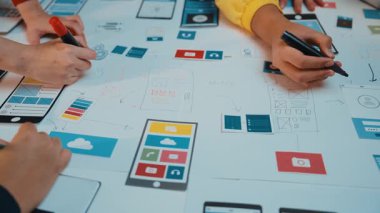 Dinamik sahne gösterici eller işbirlikçi bir tasarım oturumunda, canlı dijital modellerle çevriliyken kağıda yenilikçi kullanıcı arayüzü kavramları çiziyor. SACTR