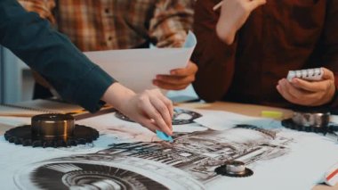 Mühendisler modern bir ofis alanında birlikte çalışırlar, fikirleri paylaşırlar ve yenilik araçları ve ekipmanlarla çevriliyken evrak işleriyle ilgili mekanik tasarımları gözden geçirirler. SACTR