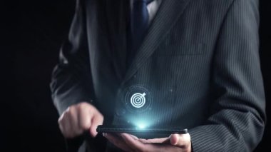 Takım elbiseli bir işadamı dijital pazarlama stratejisi arayüzü gösteren bir akıllı telefon tutuyor, yenilikçi kavramları ve modern iş dünyasının başarısı için analizleri vurguluyor. Dörtgen