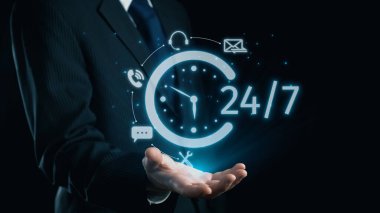 Takım elbiseli bir işadamı dinamik bir şekilde, içinde bir saat ve çeşitli teknoloji sembolleri bulunan ve modern bağlantı çözümleri gösteren 24 saatlik parlak bir servis ikonu tutuyor. Dörtgen
