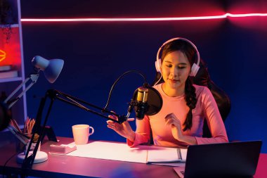 Geceleri podcast 'te olumlu konuşmalar yapan, pembe neon ışıklı modern stüdyoda sunum için dizüstü bilgisayar kullanan, gülümseyen, genç, güzel Asyalı bir etkileyiciydi. Taktik.