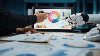 Bir insan eli, ekranda gösterilen veri grafiklerini analiz etmek için robotik bir elle işbirliği yapar. Teknolojinin modern iş analizlerinde entegrasyonunu vurgular. Noogenesis