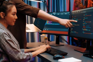 Modern ofisteki neon ışık odasında bilgi ağını gösteren dizüstü bilgisayarla iki ekranda veri çalıştıran akıllı web sitesi geliştirme kodlayıcı sistemini tartışan IT geliştiricilerinin ciddiyeti. İnfobahn.