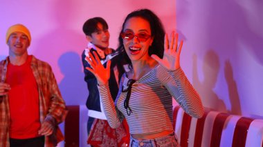 Çok kültürlü bir arkadaş birlikte dans ediyor ve hiphop müziği eşliğinde restoranda ya da kafede pembe neon ışıklı duruyor. Profesyonel sokak dansçıları grubu enerjik hareketler sergiliyor. Mutluluk.