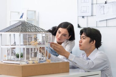 Kooperatif mühendis ekibinin portresi ev modelini ölçmek için cetvel ve mimari ekipmanlar kullanarak birlikte çalışıyor. Yaratıcı iş tasarımı ve takım çalışması konsepti. Tertemiz...