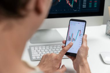 Akıllı borsa yatırımcıları ekranda akıllı telefon ile piyasa borsasını işaret ederek dizüstü bilgisayarın yanı sıra en yüksek dinamik yatırım oranını göstererek, modern işyerindeki veri planlamasına odaklanıyorlar. Bireysel.