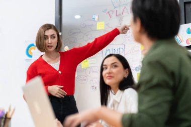 Kafkasyalı genç bir iş kadını, pazarlama stratejisini zihin haritası kullanarak sunuyor, soruları kendinden emin bir şekilde cevaplarken grafiğini çiziyor. Takım çalışması, beyin fırtınası, tartışma konsepti. Tertemiz..