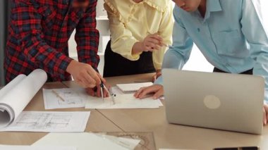 Mimarlık ve güvenlik mühendisi, modern ofiste doğruluk için mimari belge ve ölçüm aracı kullanılarak dizüstü bilgisayarın üzerinde sergilenen planlar hakkında tartıştı. - Yakın çekim. Tanımlama.