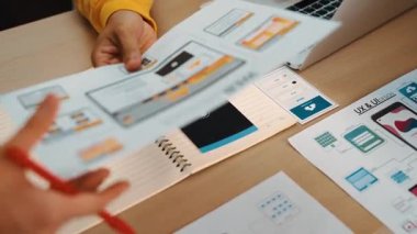 Mobil uygulama için kullanıcı arayüzü prototipini ofis çalışma alanındaki akıllı yöneticiye sunan mükemmel bir şirket çalışanı. UX UI tasarımcısı kağıt üzerinde simge tasarımının işlevini açıklıyor. Sinerjik