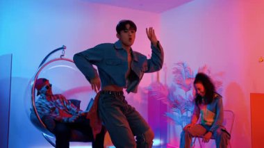 Çok kültürlü bir arkadaş kürsüde otururken Asyalı yetenekli bir dansçı modern müziğe geçiyor. Profesyonel dansçı, hipster takımı tezahürat yaparken ve desteklerken enerjik adımlar atıyor. Mutluluk.