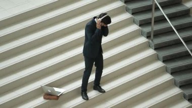 Kulaklıktan müzik eşliğinde merdivenlerde duran profesyonel bir iş adamı. Merdivenlere dizüstü bilgisayar yerleştirip dans ederken dinlenme sesi dinleyen yetenekli bir proje yöneticisi. Modern dans. Sevinçli..