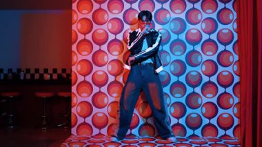 Asyalı break dansçı serbest stile geçiyor ve balon arka planlı kameraya bakıyor. Profesyonel hippi gündelik kıyafet giyer ve gözlük takar. Mutluluk.