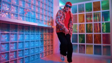 Yakışıklı, beyaz tenli sanatçı kurşun ışıkla dans etmek için dans ediyor. Güneş gözlüklü, şapkalı çılgın hippi dans ediyor ve modern gece kulübünde serbest dans dinlemenin tadını çıkarıyor. Mutluluk.