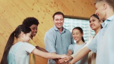 Kafkas öğretmeni ve mutlu çeşitli çocuklar ayakta dururken başarılı projeyi kutlamak için el ele tutuşuyorlar. Aşkı, şirketi, takım çalışmasını, birlikteliği ve birliği temsil et. Öğretim