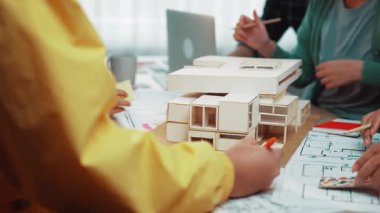 Tasarım modelleri ve planlar üzerinde işbirliği yapan, modern bir çalışma alanında yaratıcılığı ve takım çalışmasını somutlaştıran canlı bir ofis sahnesi. SACTR