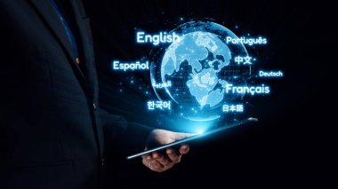 Küresel iletişim ve kültürel bağlantının önemini sembolize eden çeşitli dil çevirileriyle çevrili parlayan bir küreyi gösteren bir tablet tutan bir profesyonel. Dörtgen