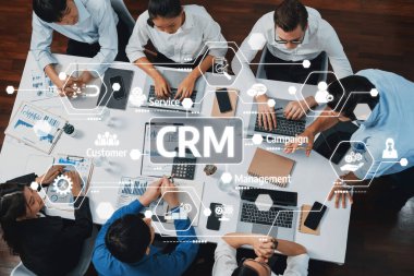 Modern ofis ortamında dijital arayüzler ve analitik araçlarla çevrili CRM sistem geliştirme üzerinde çalışan bir iş ekibinin tepeden tırnağa görüntüsü. Dostluk