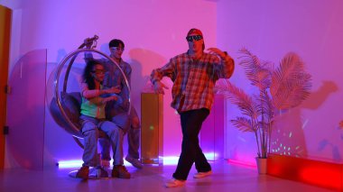 Stüdyoda gündelik kıyafetleri olan çok kültürlü bir arkadaş tezahürat yaparken mutlu hipster break dansları. Profesyonel sokak dansçısı hip hop ritmi ya da neon veya kurşun ışıkla kafiyeli bir şarkı söyler. Mutluluk.