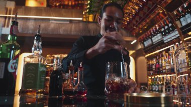 Zeki Asyalı barmen bardakta karıştırılmış alkol şurubunu buzla karıştırıyor. Çünkü kayanın üzerinde kamera var. Gece kulübünde taze kokteyl kokteylleri karıştırıyor. Vinosity.