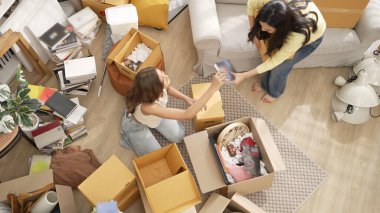 Kızlar oturma odasında birlikte yardım ederken yeni eve taşınmaya bayılırlar. Diğeri kitabı seçip sevgilisine gönderirken birkaç lezbiyen nezaret kutusunun en üst görüntüsü. Yer değiştirme konsepti. Myrmidon.