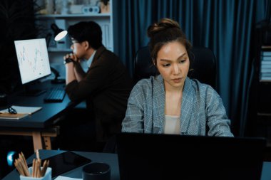 Modern ofiste gece geç saatlerde arka tarafta çalışan iş arkadaşı ile birlikte veri analizi sosyal medya çevrimiçi proje işini rapor etmek için bilgisayara odaklanan iş kadınının ciddi yüzü. İnfobahn.