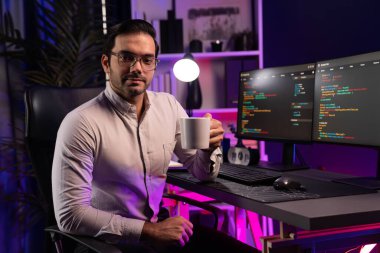 Bilgisayar ekranındaki yazılım geliştirme kodlarında kahve fincanı tutan akıllı bilişim geliştiricisi profili. Program güncellemesi internet sitesi verilerini neon ışığı siber ofisinde sunuyor. Tahmin et..