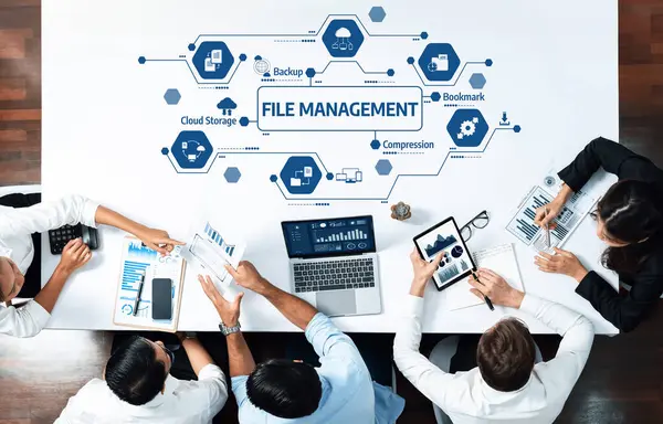 Çeşitli bir ekip, modern ofis ortamında üretkenliği ve aerodinamik süreçleri geliştirmek için teknoloji ve veri görsellerinden yararlanmak üzere dosya yönetimi stratejileri üzerinde işbirliği yapmaktadır. Dostluk