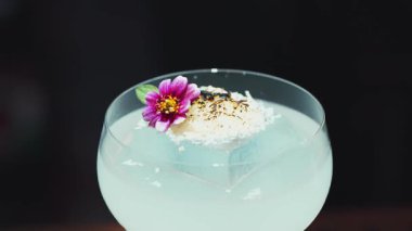 Dönüşümlü karışık kremalı votka kokteyl bardağı üzerine pembe çiçek ve buzda yanmış şeker, alkol serinletici vitrin odaklı reklamı için özel içecek listesi yapıyor. Vinosity.