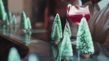 Noel ağacının yeşil neon karlı bayram reklamının yanında lüks tezgahta servis edilen şeker kamışı ve tarçınla süslenmiş karışık punç kokteyli teması. Vinosity.