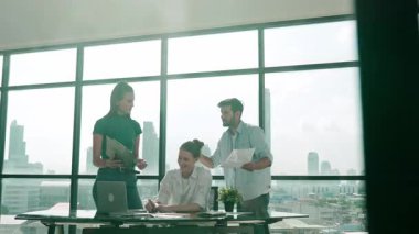 Bir grup yetenekli iş adamı toplantı masasında dizüstü bilgisayar ve istatistik belgeleriyle mali istatistik hakkında tartışıyor, beyin fırtınası yapıyor, fikir paylaşıyor, plan yapıyor ve strateji geliştiriyor. Şehir manzarası. İzleme