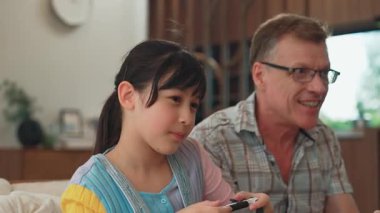 Büyükbaba ve torun birlikte konsol oyunu, eğlence medyası oynuyorlar. Eski kullanım teknolojisi yeni nesil ile iletişim kurar. Nesiller arası uçurum aile bağını güçlendirir. Uyumsuzluk.