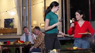 Anne ve büyükanne, aile üyeleri yıldönümü kutlamalarında yemek yerken ızgara yapıyor. Güzel akrabalarla vakit geçirmek için açık hava kamp aktiviteleri kuşaklar arası fark yaratır. Uyumsuzluk.