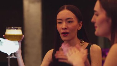 Güzel bir kadın, elinde bir bardak hindistan cevizli, köpüksüz içecek olan bir arkadaşıyla karışık çarkıfelek meyveli kokteyli hazırlıyor. Gece kulübü tezgahı partisinde canlı bir sohbete girişiyor. Vinosity.