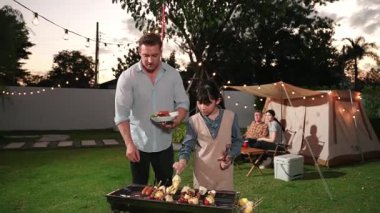 Aile birlikte bahçede kamp kurar, baba ve kız aile bireyleri için ızgara yapar. Doğayla iç içe olmak için açık hava kamp aktiviteleri ve genç nesil çapraz kuşaklarla zaman geçirmek için. Uyumsuzluk.