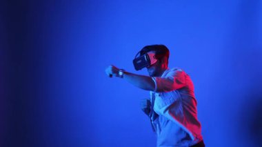 Yetenekli bir oyuncu sanal gerçeklik teknolojisi kullanarak yumruk duruşunda bulunuyor. Havalı giyinen, spor yapan ve meta-dünyaya girerken boks yapan akıllı erkek modelin yan görüntüsü. Aygıt.